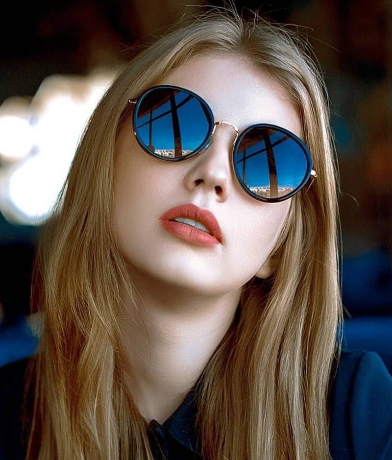 A woman wearing a pair of round sunglasses